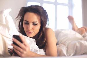 donna rilassata a casa leggendo un messaggio di testo