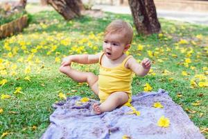 stile di vita ritratto di adorabile poco caucasico ragazza è giocando su un' plaid a estate nel parco con giallo fiori foto