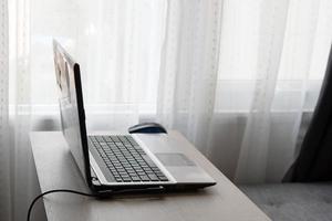 casa ufficio concetto. opera a partire dal casa su il tavolo con il computer portatile e grigio divano vicino per finestra. foto