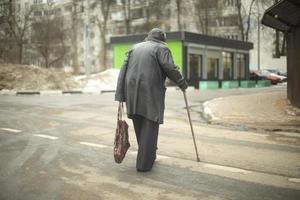 vecchio donna passeggiate giù strada nel nero giacca. pensionato nel Russia su strada. foto