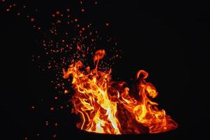 fuoco di bivacco ardente a notte, fiamma e fuoco scintillii, nero cielo, copia spazio foto