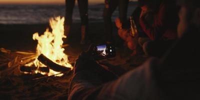 coppia assunzione fotografie accanto fuoco di bivacco su spiaggia