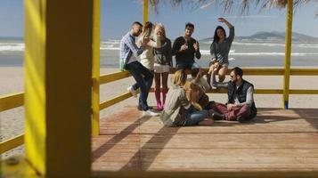 gruppo di amici avendo divertimento su autunno giorno a spiaggia foto