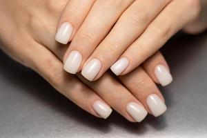 bellissimo nudo manicure. corto piazza chiodo. chiodo design. manicure con gel polacco. avvicinamento di il mani di un' giovane donna con un' delicato nudo manicure su sua chiodo. elegante Chiodi con gel polacco. foto