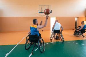 Disabilitato guerra veterani misto gara e età pallacanestro squadre nel sedie a rotelle giocando un' formazione incontro nel un' gli sport Palestra sala. portatori di handicap persone reinserimento e inclusione concetto foto