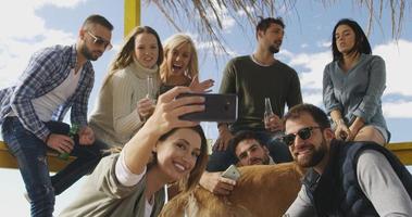 gruppo di amici avendo divertimento su autunno giorno a spiaggia foto