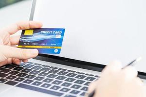 primo piano delle mani femminili che tengono la carta di credito che effettua il pagamento online foto