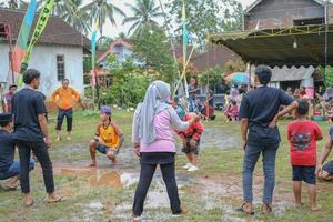 blitar, indonesia - settembre 11 ° 2022 genitori e giovane uomini nel nero magliette applauso il concorrenti su il vivace indonesiano indipendenza giorno evento nel il pomeriggio nel blitar foto