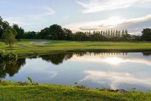 Visualizza di golf corso con fairway e stagno a tramonto, golf corso con un' ricco verde torba bellissimo scenario, verde erba e boschi su un' golf campo foto