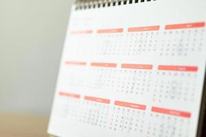 calendario pagina vicino su su legna tavolo con bianca parete sfondo attività commerciale pianificazione appuntamento incontro concetto foto