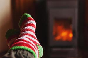 piedi gambe nel inverno Abiti lana calzini a camino sfondo. donna seduta a casa su inverno o autunno sera rilassante e riscaldamento su. inverno e freddo tempo metereologico concetto. hygge Natale vigilia. foto