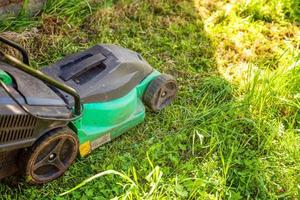 prato falciatore taglio verde erba nel Giardino dietro la casa nel soleggiato giorno. giardinaggio nazione stile di vita sfondo. bellissimo Visualizza su fresco verde erba prato nel luce del sole, giardino paesaggio nel primavera o estate stagione. foto