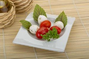 caprese insalata nel un' ciotola su di legno sfondo foto