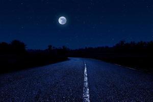 vuoto strada attraverso foresta a notte. foto