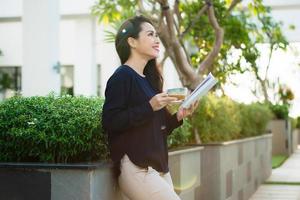 contento giovane donna Tenere libro affettuoso di letteratura analizzando romanzo durante tempo libero tempo su terrazza di città universitaria bar nel soleggiato giorno. foto