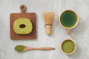 matcha verde tè latte macchiato nel un' tazza e tè cerimonia utensili con Tedesco torta. copia spazio foto