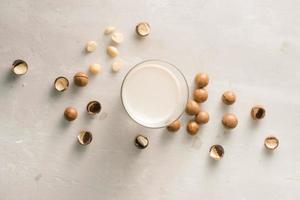 supercibo. biologico macadamia noccioline e bicchiere di macadamia latte su pietra sfondo. foto