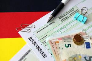 Tedesco reddito imposta ritorno modulo con penna e europeo Euro i soldi fatture bugie su bandiera vicino su. contribuenti nel Germania utilizzando Euro moneta per pagare le tasse foto