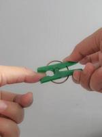 un' mano cerca per pizzico il suo pollice utilizzando un' verde molletta. foto