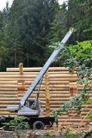 il processi di edificio un' di legno Casa a partire dal di legno travi di cilindrico forma. gru nel Lavorando condizione foto