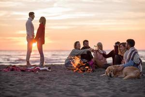 coppia godendo con amici a tramonto su il spiaggia foto