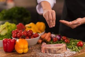 capocuoco mettendo sale su succoso fetta di crudo bistecca foto