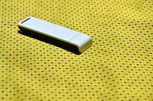 un' moderno portatile USB Wi-Fi adattatore è posto su il giallo abbigliamento sportivo fatto di poliestere nylon fibra foto
