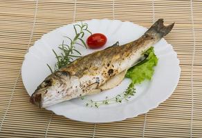 branzino alla griglia sul piatto e fondo in legno foto