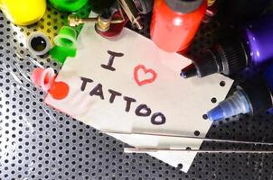 io amore tatuaggio. il testo è scritto su un' piccolo foglio di carta tra vario attrezzatura per tatuaggio foto