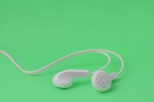 un' modello per musica ascoltando fan. bianca auricolari su verde foto