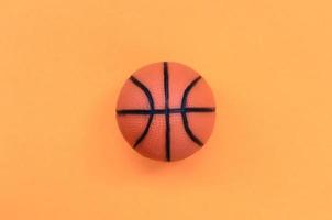 piccolo arancia palla per pallacanestro sport gioco bugie su struttura sfondo di moda pastello arancia colore carta nel minimo concetto foto