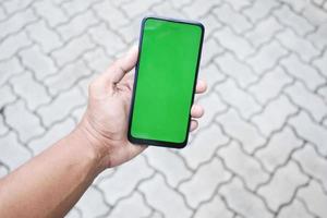 primo piano della mano del giovane che utilizza lo smartphone con lo schermo verde foto