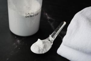 lavaggio polvere nel plastica cucchiaio e asciugamano su nero sfondo foto