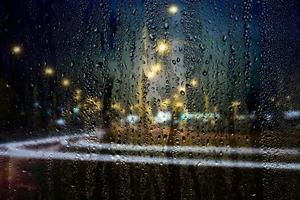 piovoso finestra, gocce di pioggia su il bicchiere su il sfondo di il autostrada senza pedaggio. sicuro modo casa. foto