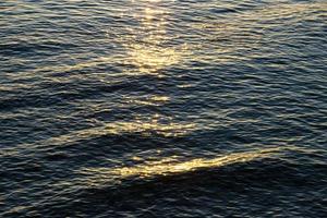 mare onde, riflessione di luce del sole a partire dal il superficie di il acqua durante tramonto. rosso mare. marino sfondo. foto