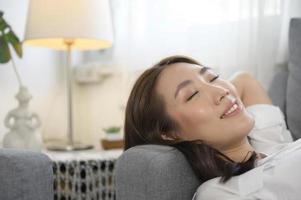 giovane asiatico donna napping su il divano nel vivente camera , contento salutare stile di vita concetto foto