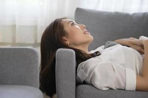 giovane asiatico donna napping su il divano nel vivente camera , contento salutare stile di vita concetto foto