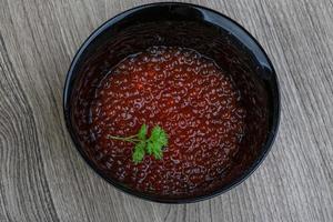 caviale rosso in una ciotola su fondo di legno foto