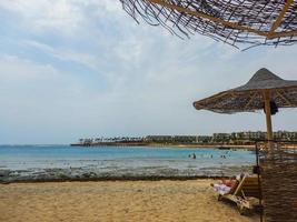 Visualizza per il mare a partire dal il spiaggia mentre dire bugie sotto un' spiaggia ombrello foto