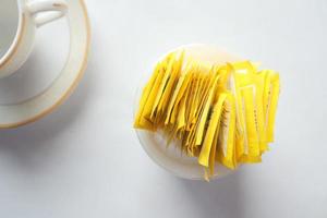 zucchero sostituto dolcificante pacchetto e tè tazza su bianca sfondo foto