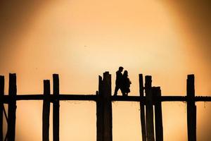 silhouette di un' coppia a piedi su il u bein ponte con tramonto crepuscolo cielo nel sfondo, mandala, Myanmar foto