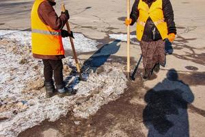 un' donna lavoratore pulisce il ghiaccio e rimuove neve a partire dal pavimentazione lastre utilizzando un rompighiaccio. foto