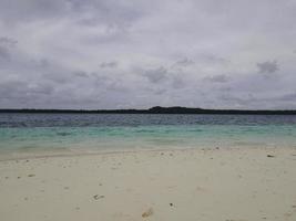 bellissimo soleggiato giorno su un' calma incontaminato spiaggia con grigio cieli nel Indonesia foto