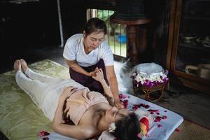 massaggio e spa trattamento rilassante della sindrome dell'ufficio tradizionale stile di massaggio tailandese. asain massaggiatrice femminile che fa massaggi cura mal di schiena, dolore alle braccia e stress per la donna dell'ufficio stanca dal lavoro. foto