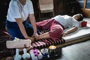 piede massaggio e terme rilassante trattamento di ufficio sindrome tradizionale tailandese massaggio stile. asiatico anziano femmina massaggiatrice fare piedi massaggio trattare piede e fatica per vecchio donna stanco. foto