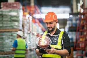 professionale manager uomo dipendente utilizzando tavoletta dai un'occhiata azione Lavorando a magazzino. lavoratore indossare alto visibilità capi di abbigliamento e un' difficile cappello, casco e controllo e contare su merce o scatole per consegna. foto