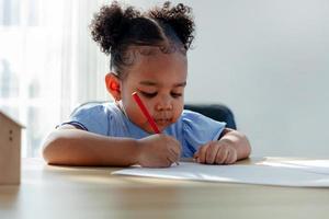 africano bambini siamo disegno e fare loro compiti a casa nel il aula. un' giovane ragazza gode apprendimento e giocando con disegni su carta. foto