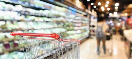 supermercato negozio di alimentari con scaffali di frutta e verdura interno sfocato sfondo con carrello rosso vuoto foto