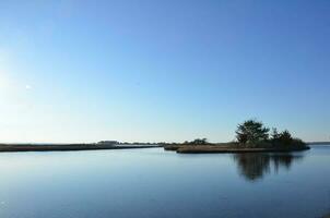 un' lago o fiume con Marrone erbe e riva foto