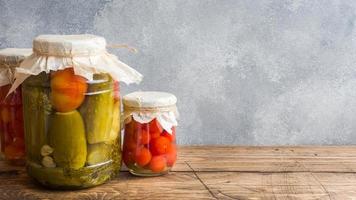 fatti in casa in scatola verdure nel lattine. sottaceto pomodori e cetrioli nel un' rurale stile. copia spazio foto